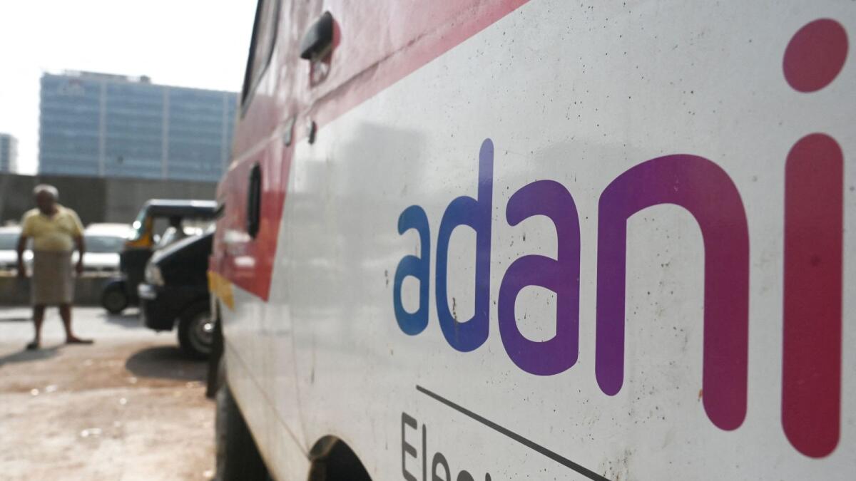 People walk past a parked van with the signage of Indian conglomerate Adani in Mumbai. - AFP