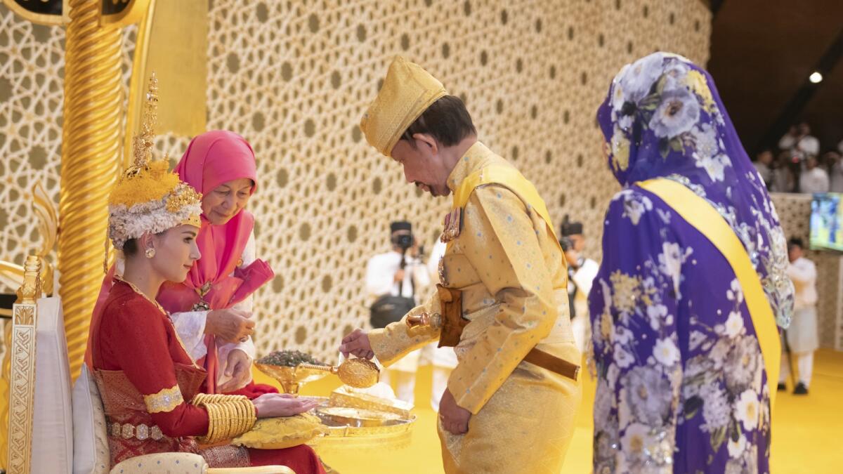 Brunei's Sultan Hassanal Bolkiah, centre right, pouring scented oil on the hands of prince's bride Yang Mulia Anisha Rosnah ahead of the wedding. — AP