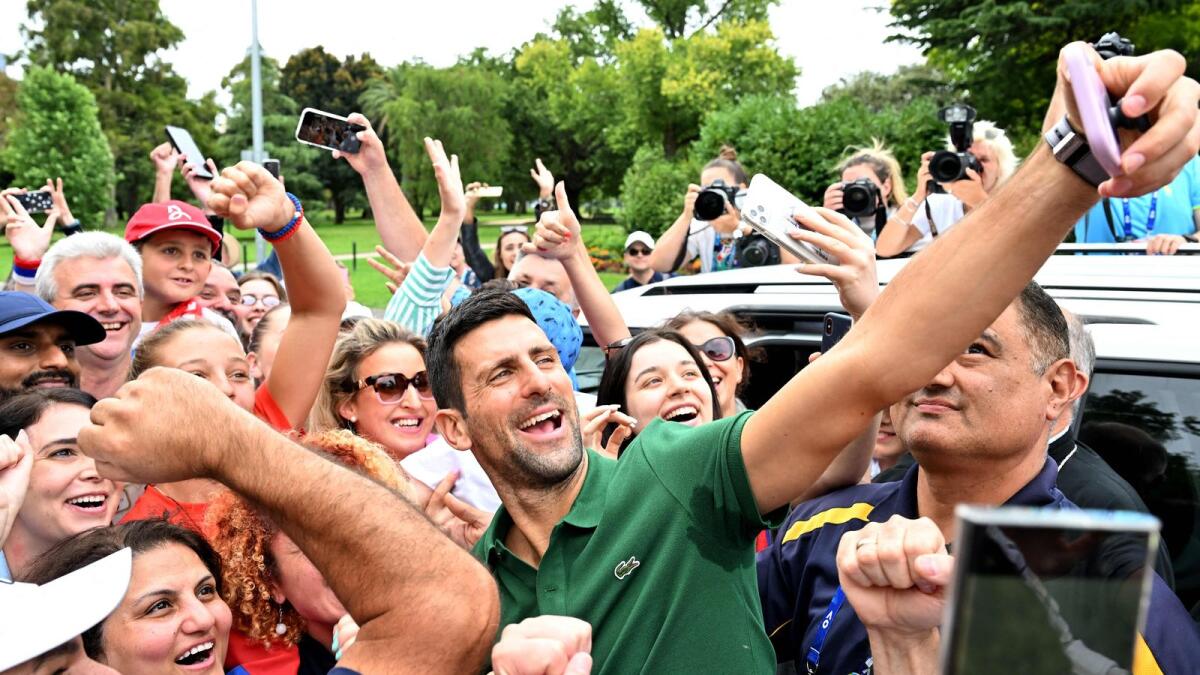 Novak Djokovic takes selfies with his supporters outside the Government House in Melbourne. — AFP