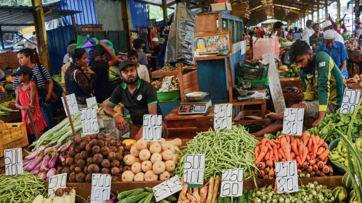 Vendors sell vegetables at a market in Colombo. — AFP file