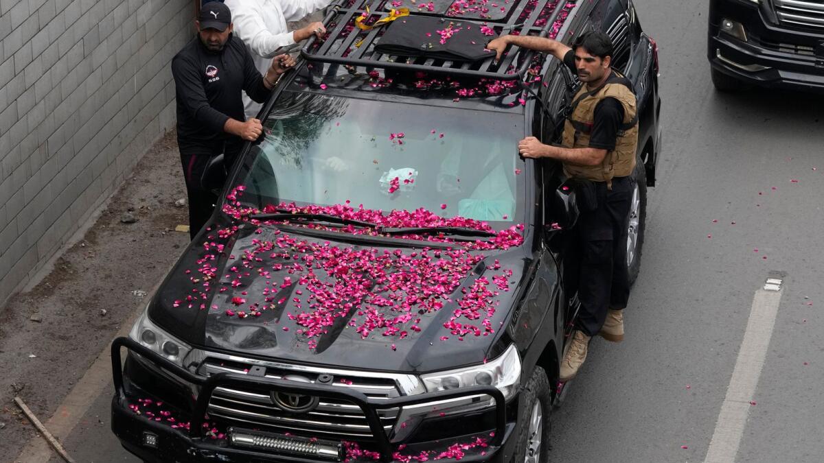 Security personnel climb on a vehicle carrying former prime minister Imran Khan as it moves toward Islamabad at a road in Lahore, Pakistan, Saturday, March 18. — AP