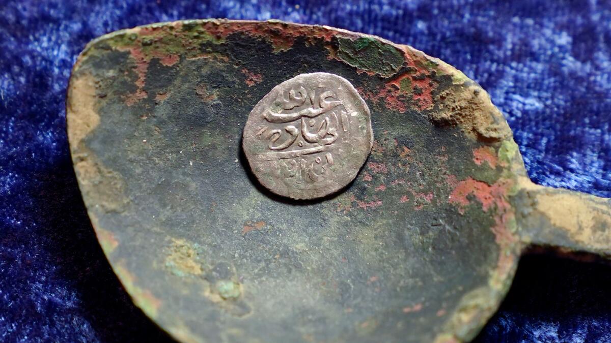 A17th century Arabian silver coin that research shows was struck in 1693 in Yemen, rests in a 17th century brass spoon on a table, in Warwick, R.I., on Thursday.