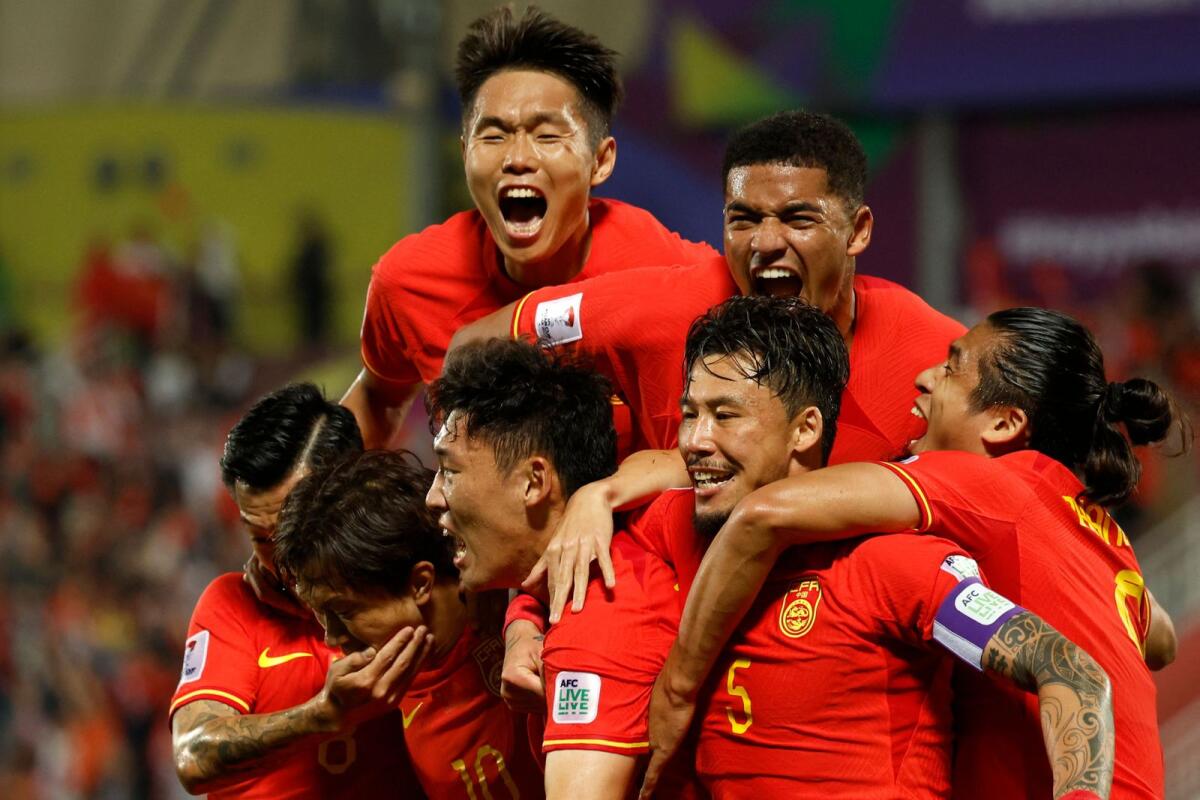 China's defender Zhu Chenjie (C bottom) celebrates with his teammates after scoring a goal, which was later disallowed, during the Qatar 2023 AFC Asian Cup Group A match against Tajikistan. - AFP