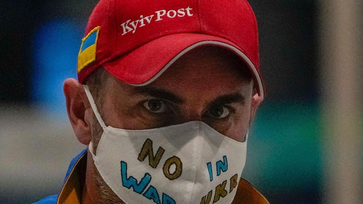 A Ukrainian journalist wearing a face mask bearing the words 'No War in Ukraine' walks through the Main Media Centre ahead of the 2022 Winter Paralympics in Beijing, China. (AP)