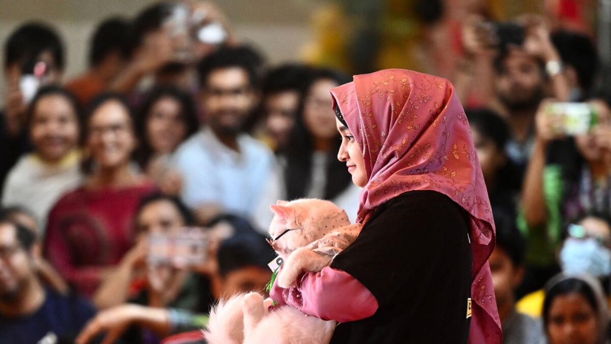 A participant walks the ramp holding her pet cat during a cat show in Dhaka. — AFP