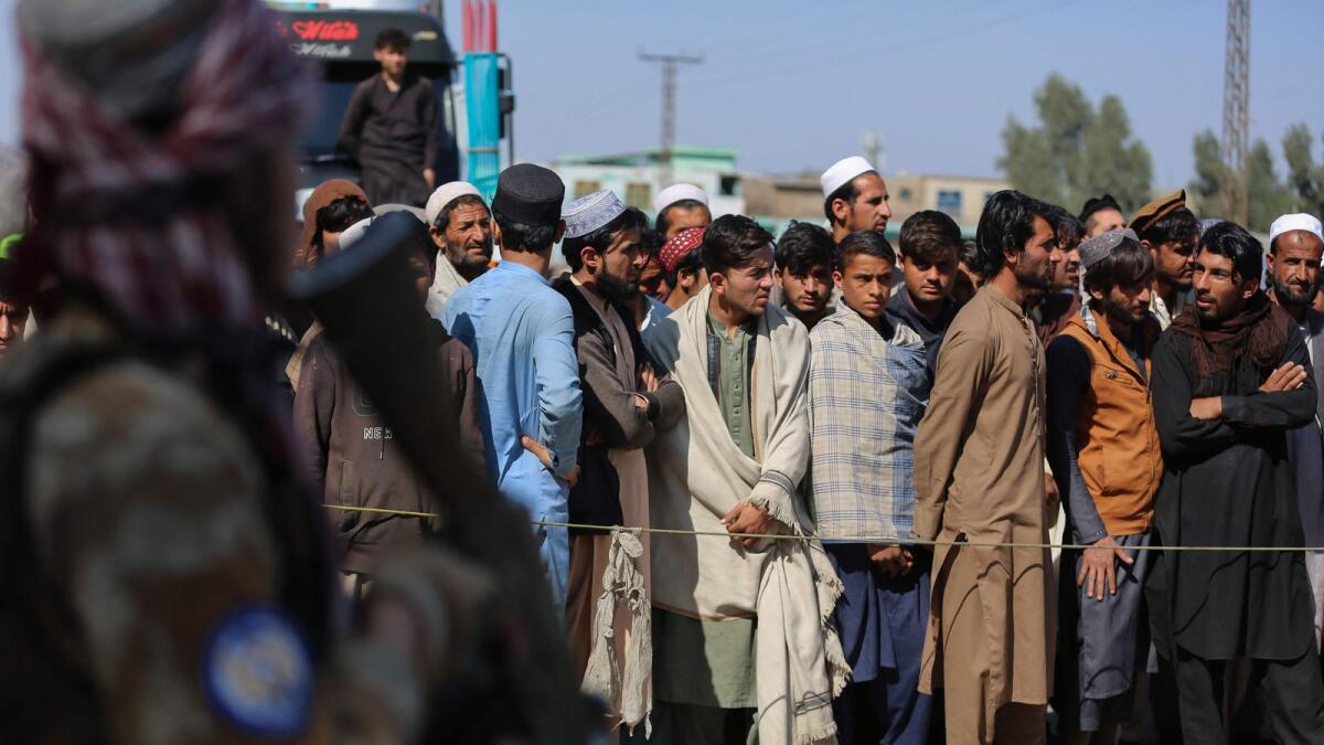 Afghan people stand as they wait to cross into Pakistan, near the closed Torkham gate, in Afghanistan’s Nangarhar province on Thursday. — AFP