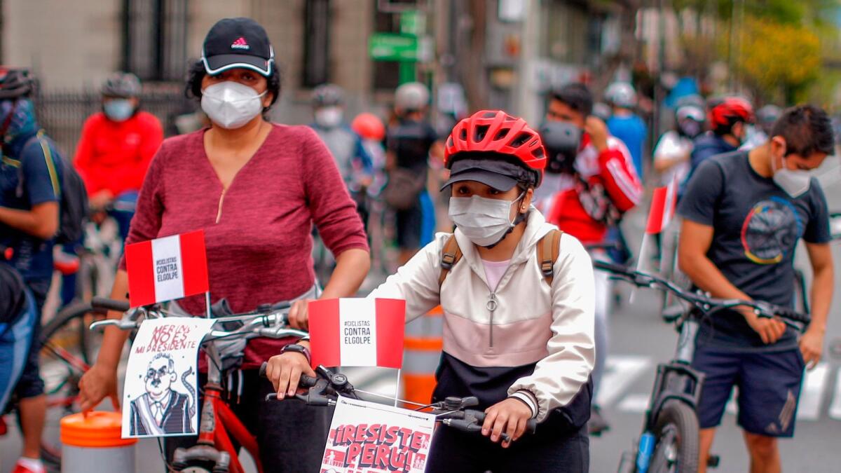 Protesters take signs on their bicycles reading 'Merino is Not My President' (L) and 'Peru Resist' during a peaceful demonstration against the new government of interim president Manuel Merino in Lima.