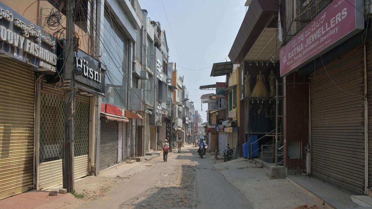Closed shops are seen along a strret in Bangalore following Karnataka's government announcement of a complete lockdown. Photo: AFP