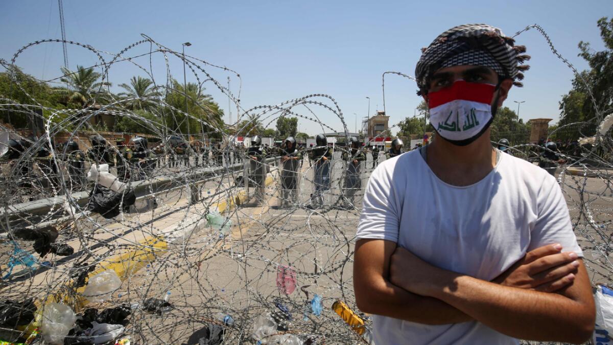 An Iraqi man stands in front of security forces during a protest outside the Green Zone in Baghdad on July 12, 2020 to demand a curb on paramilitary groups and restricting the use of weapons to government security forces. Photo: AFP