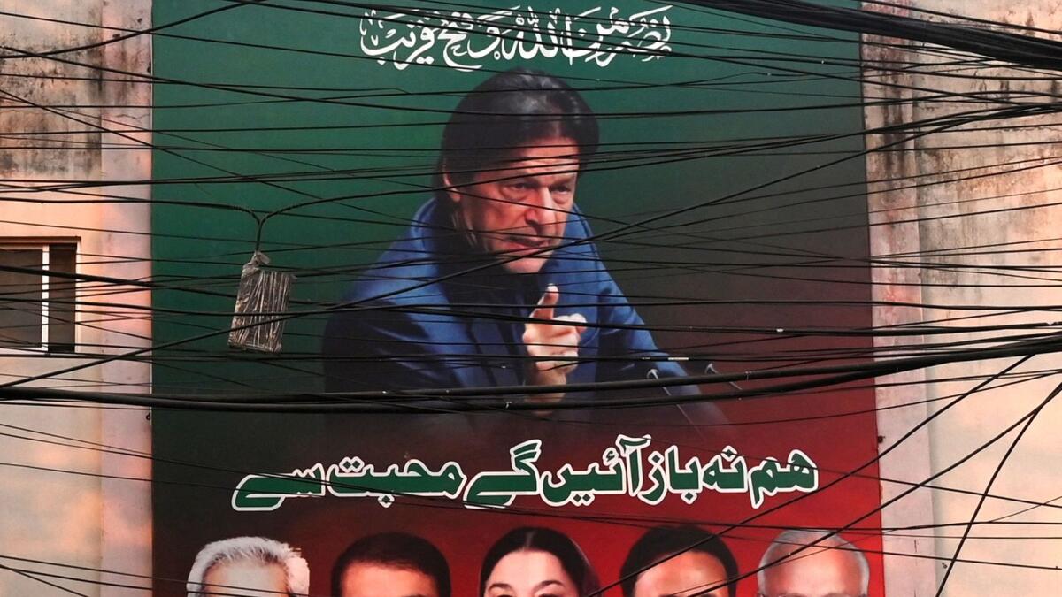 A poster of Pakistan's ex-prime minister Imran Khan is seen through cables in Lahore. — AFP