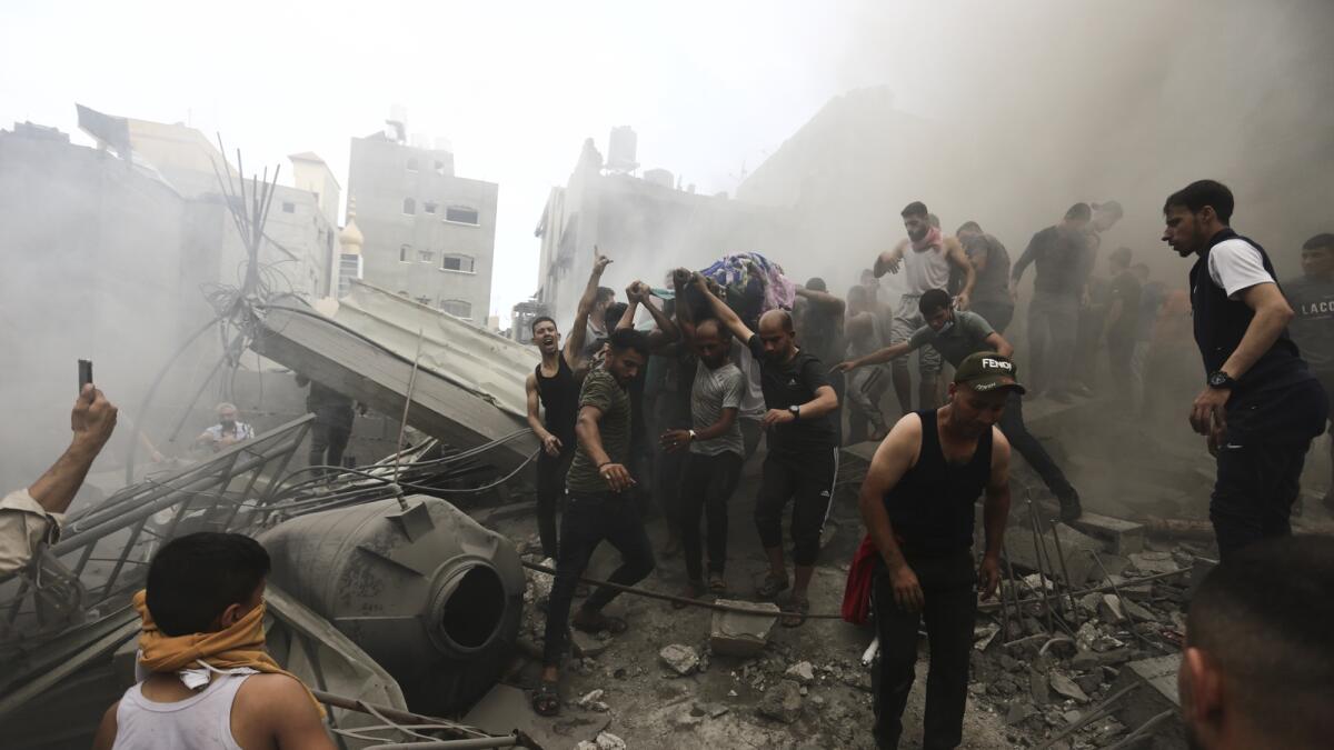 Palestinians remove a dead body from the rubble of a building after an Israeli airstrike Jebaliya refugee camp. — AP
