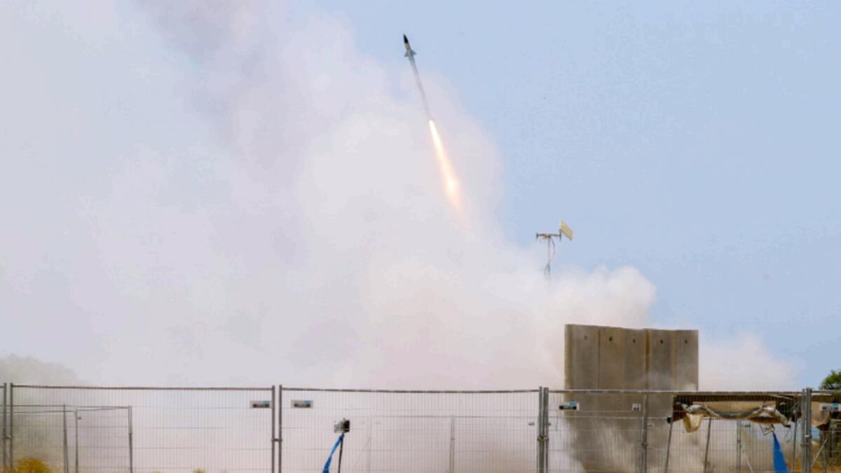 An Israeli soldier takes cover as an Iron Dome air defence system launches to intercept a rocket from the Gaza Strip. — AP