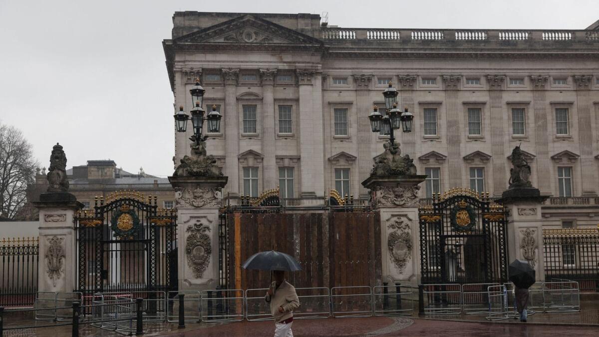 A pedestrian walks past a boarded-up gate at Buckingham Palace after a car drove into it. — Reuters