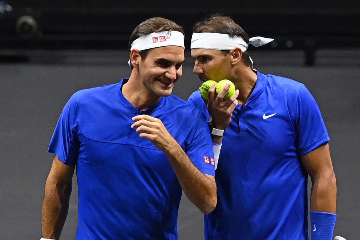 Roger Federer (left) gets instructions from Rafael Nadal during their doubles match. (AFP)