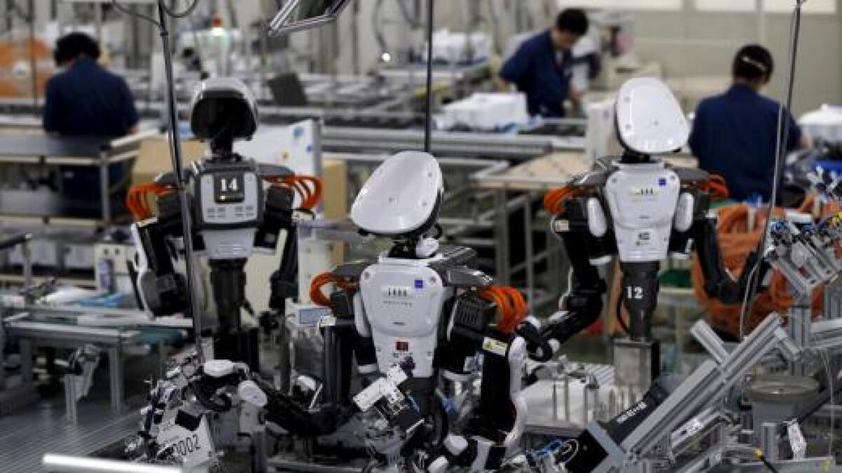 Humanoid robots work side by side with employees on the assembly line at a factory