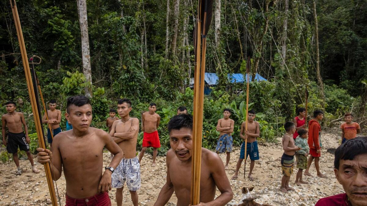 About two dozen Yanomami people, who emerged from the rainforest when members of Brazil’s environmental special forces team arrived to destroy illegal mining equipment in the Yanomami Indigenous territory of Brazil, on Feb. 24, 2023. An explosion of illegal mining in this vast swath of the Amazon has created a humanitarian crisis for the Yanomami people, cutting their food supplies, spreading malaria and, in some cases, threatening the Yanomamis with violence, according to government scientists and officials. (Victor Moriyama/The New York Times)