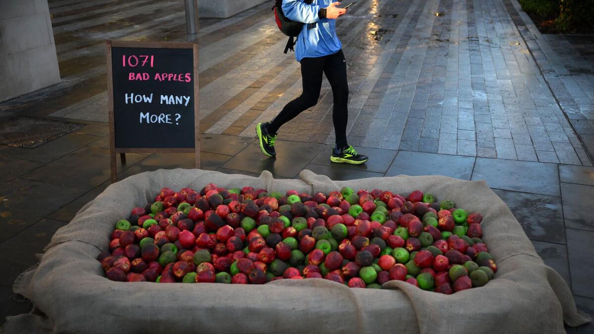 1,071 mock rotten apples are pictured outside New Scotland Yard in London on Friday to reflect the number of Metropolitan Police officers who have been, or currently are, under investigation for allegations of domestic abuse or violence against women and girls. — AFP