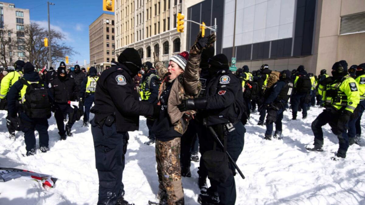 A protester sings national anthem of Canada, as they are arrested after trying to push through line of police officers as they aim to end an ongoing protest against Covid-19 measures. — AP