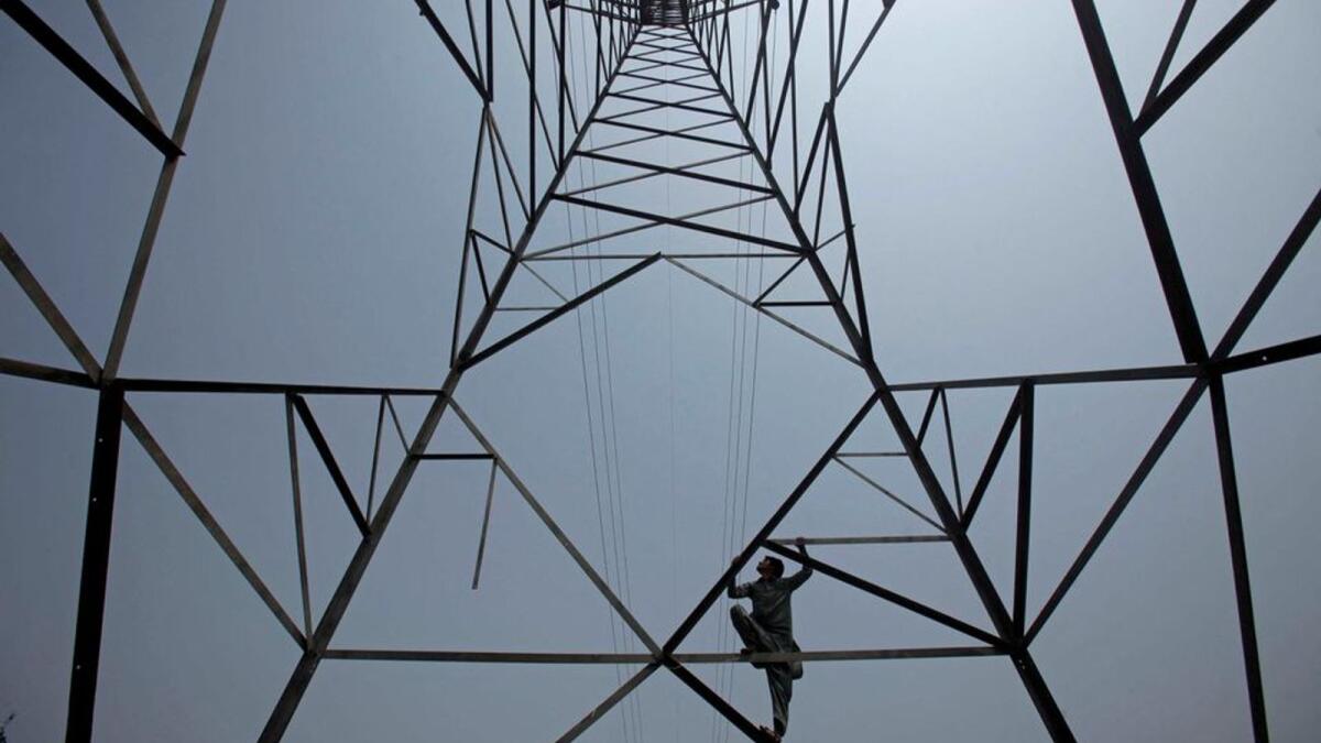 A worker of Peshawar Electric Supply Company climbs up a high-voltage pylon in Peshawar, Pakistan. Photo: Reuters