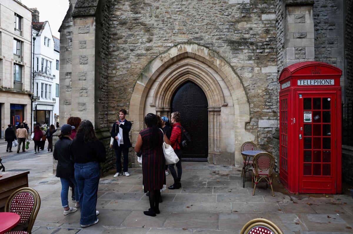 Tour guide Oliver talks to a group of people attending an 'Uncomfortable Oxford' tour outside the Carafe Tower in Oxford on October 20, 2023.— AFP