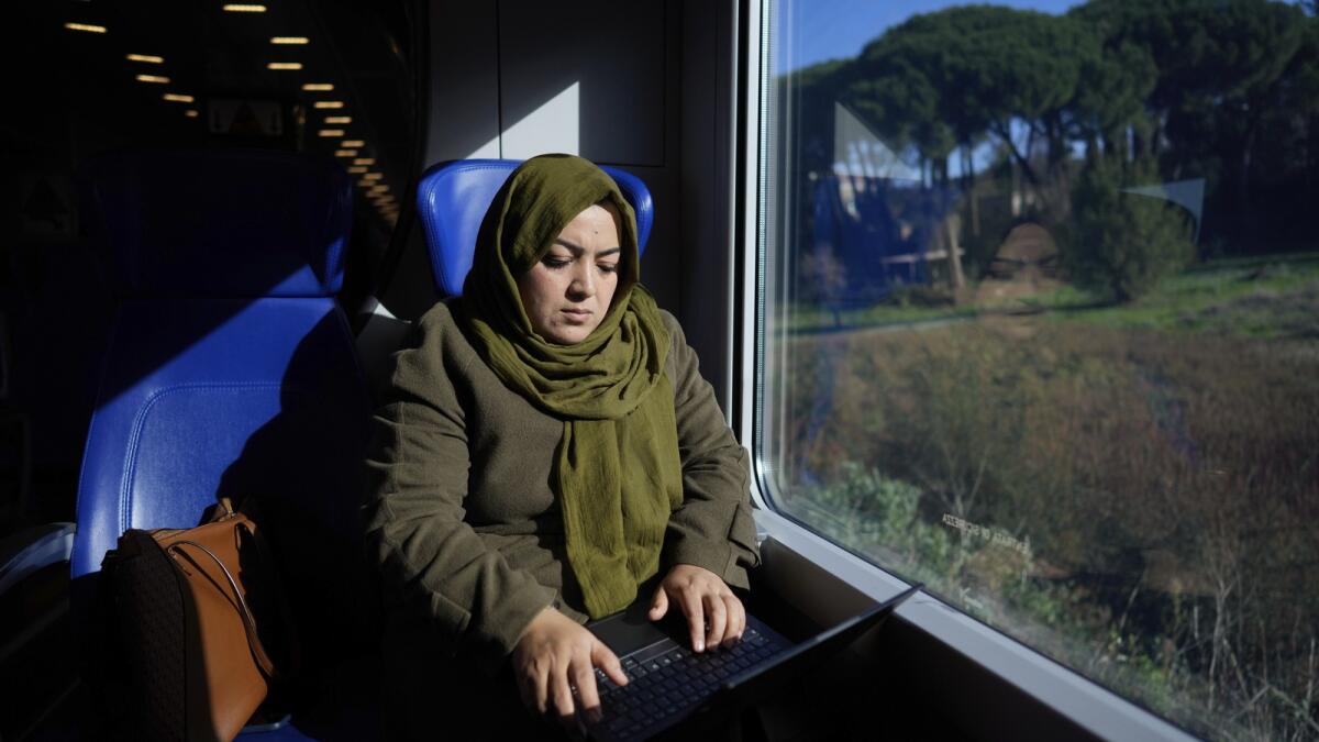 Batool Haidariworks at her laptop on a train taking her from her home on the outskirts of Rome. — AP