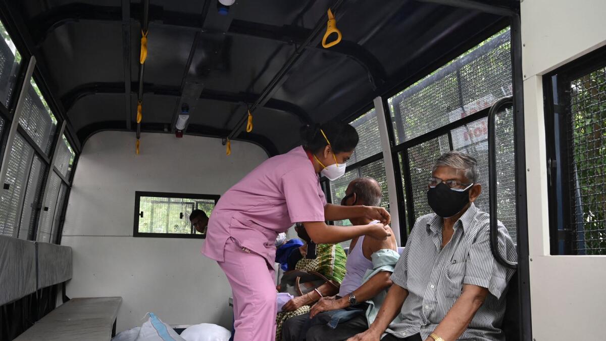 A health worker inoculates an elderly man inside a police van in the Maidan area in Kolkata. Photo: AFP