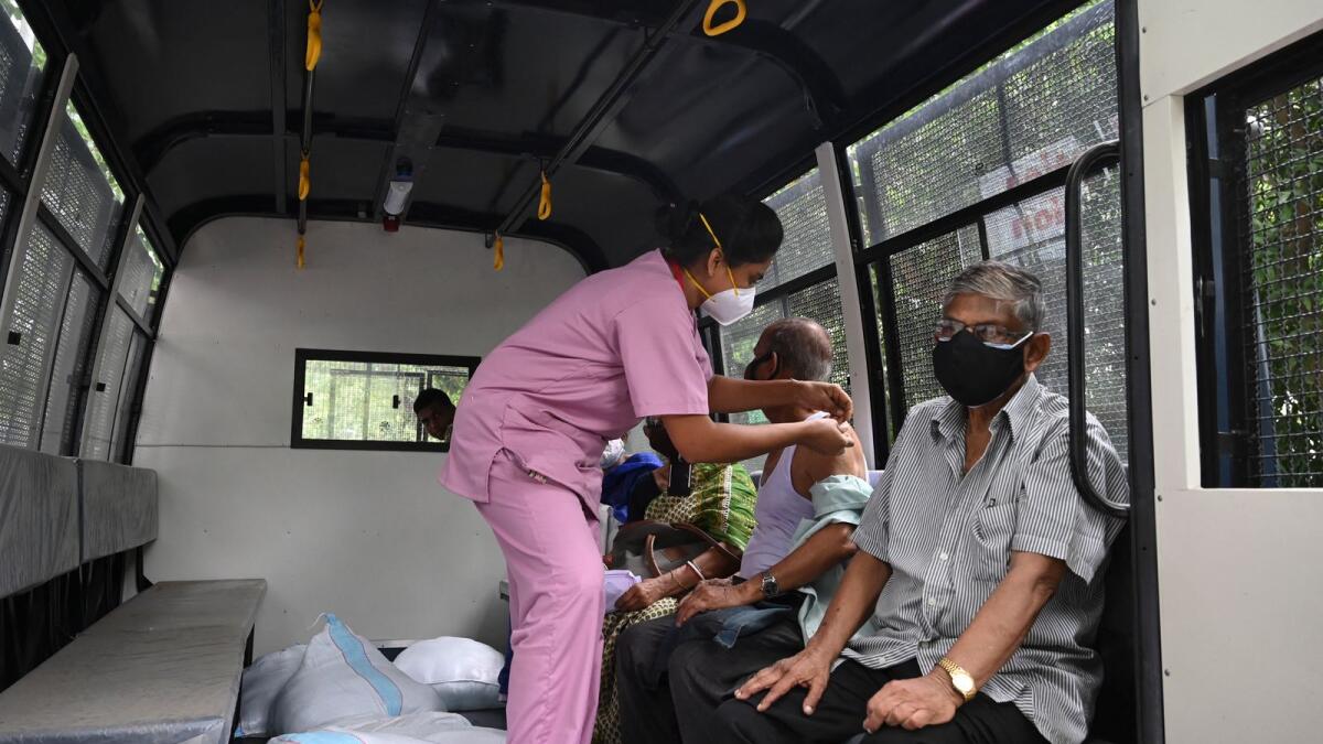 A health worker inoculates an elderly man inside a police van in the Maidan area in Kolkata. Photo: AFP