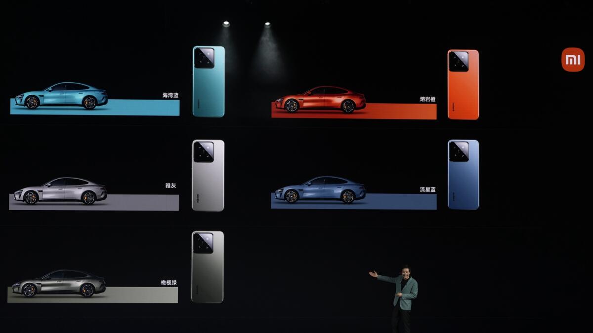 Xiaomi founder Lei Jun shows off the colours of the SU7, a sporty four-door sedan, with matching Xiaomi smartphones. — AP
