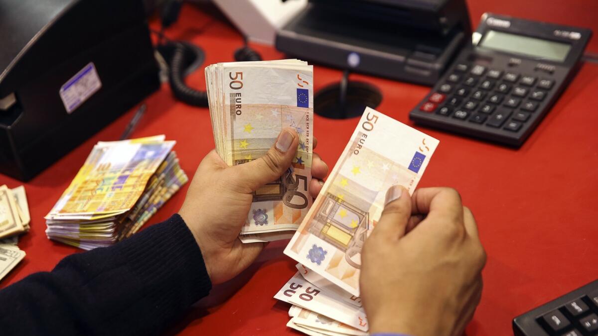 An employee counts fifty euro banknotes as he works at his desk in this arranged photograph taken inside a Travelex store, operated by Travelex Holdings Ltd., in London, U.K., on Monday, Jan. 12, 2015. The euro approached a nine-year low against the dollar as European Central Bank officials fueled speculation the institution will start a program of government-bond buying as early as next week to stave off deflation. Photographer: Simon Dawson/Bloomberg