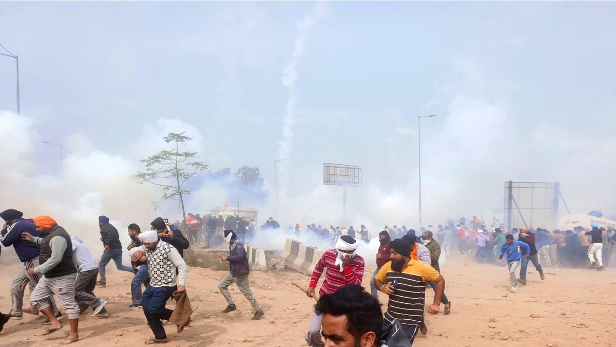 Farmers run for cover after police fired tear gas to disperse them near the Punjab-Haryana border at Shambhu, India. — AP