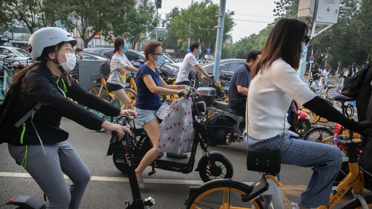 People wearing face masks to protect against the coronavirus wait at an intersection in Beijing. China reported more than 100 new cases of Covid-19 on Wednesday as the country continues to battle an outbreak in Xinjiang. Photo: AP