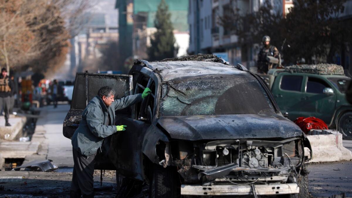 An Afghan security member inspects a damaged vehicle after a bomb blast in Kabul, Afghanistan, December 13.