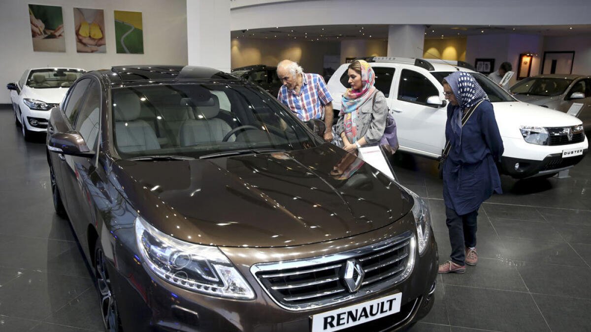 Iranians look at a Renault sedan at a dealership in northern Tehran, Iran.