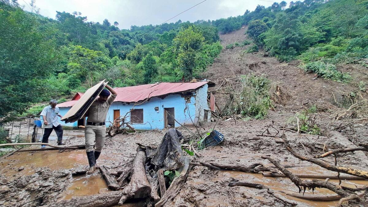 A security personnel carries the belongings of a villager from the site of a landslide after heavy rains at Jadon village in Solan district of Himachal Pradesh. — AFP