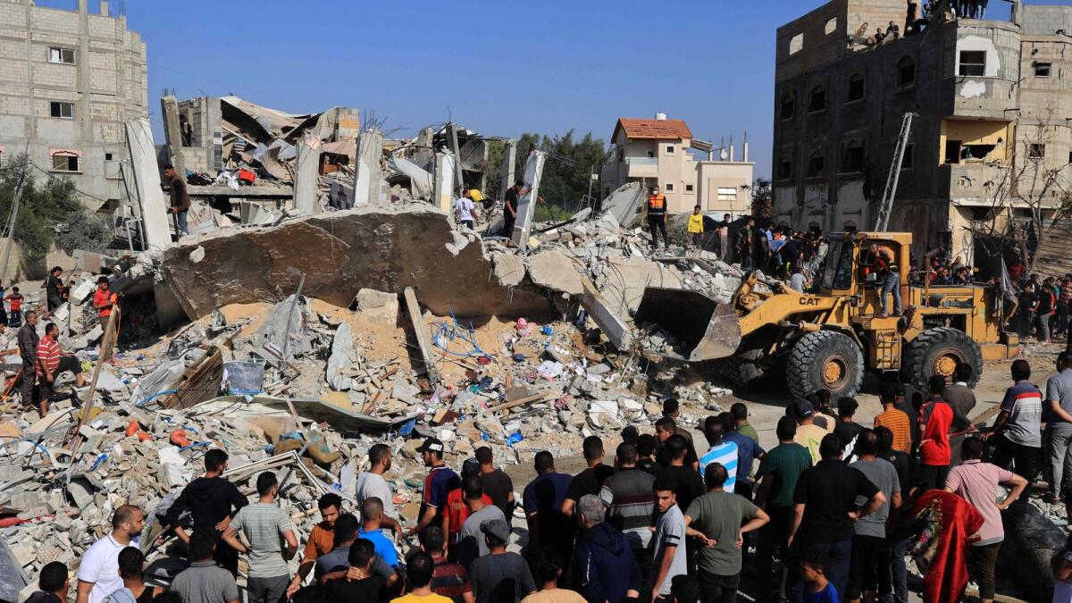 Palestinians rescuers look for survivors as others watch a digger remove concrete blocks after an Israeli strike on Rafah, in the southern Gaza Strip, on November 9. — AFP