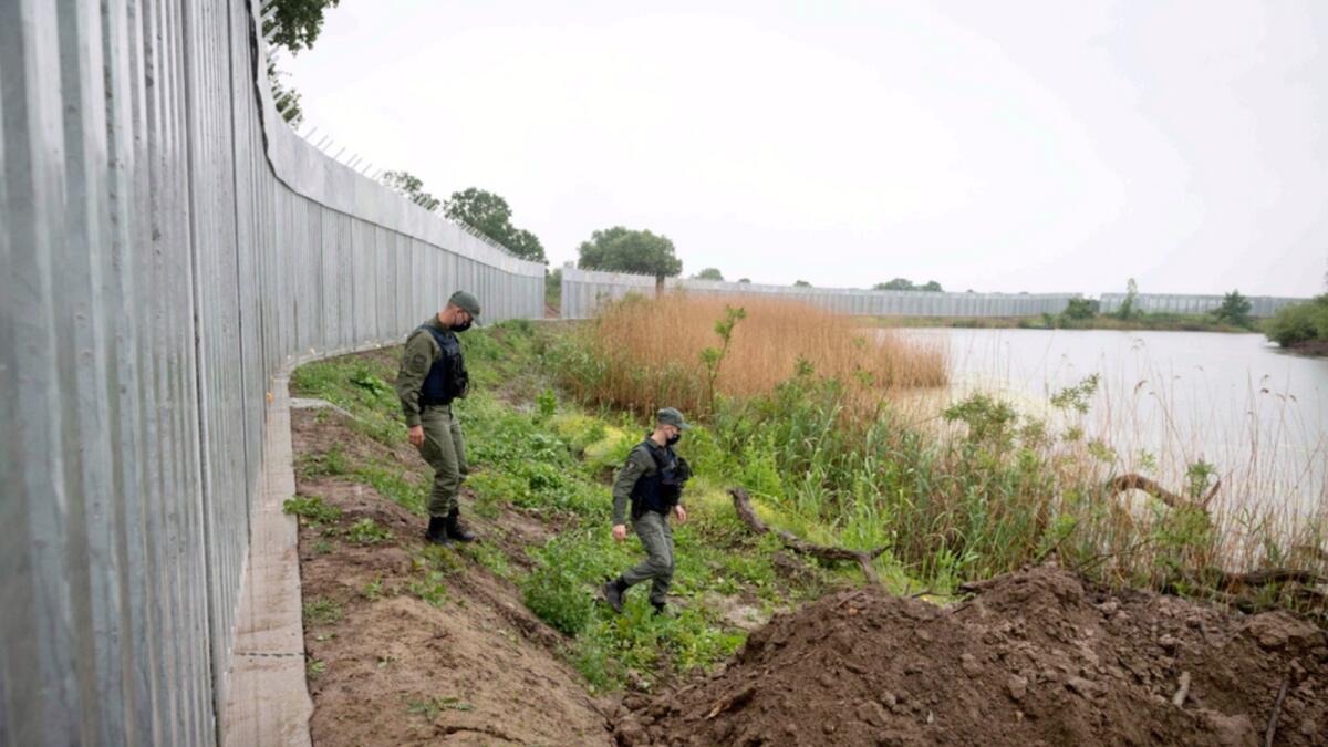 Policemen patrol alongside a steel wall at Evros river, near the village of Poros, at the Greek -Turkish border. — AP file