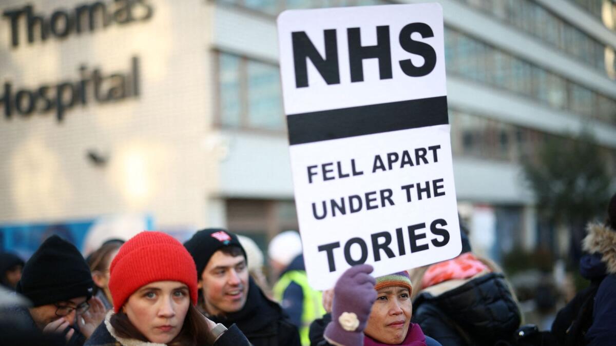NHS nurses hold a placard during a strike, due to a dispute with the government over pay,. — Reuters