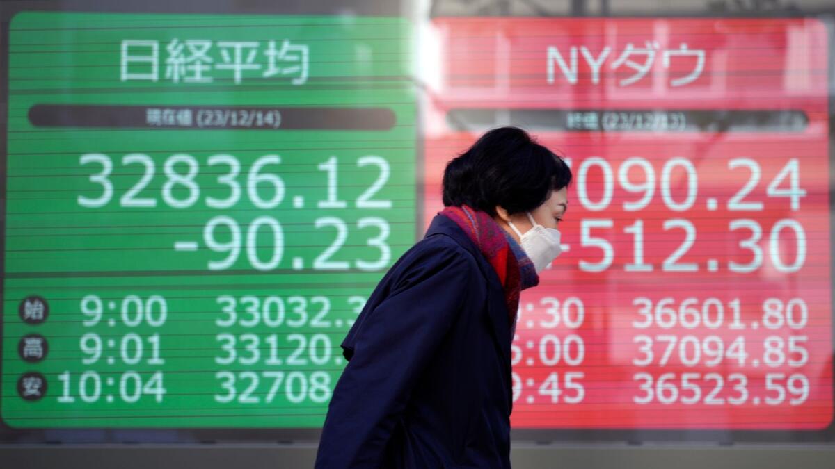 A person walks near an electronic stock board showing Japan's Nikkei 225, left, and New York Dow indexes at a securities firm in Tokyo.  — AP