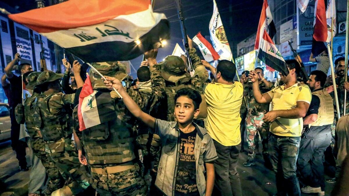 Iraqi security and civilians celebrate by waving the national flag as they wait for the final announcement of the defeat of the Daesh in Mosul, the group’s de facto capital in Iraq. —AP
