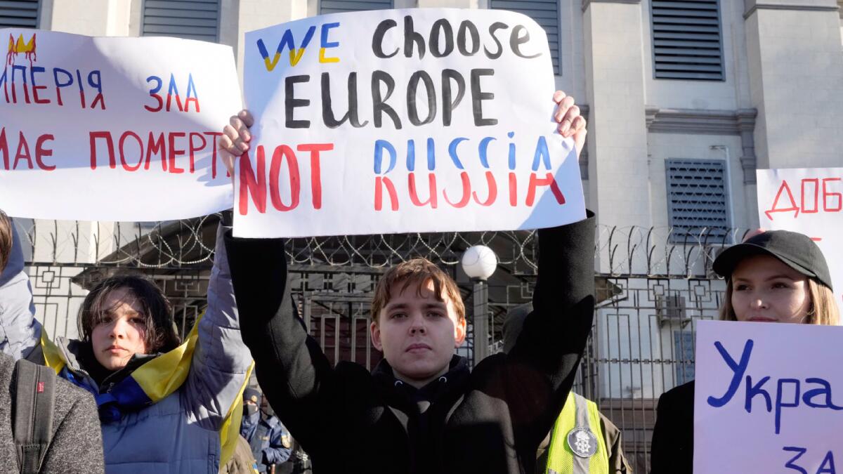 Protesters hold posters in front of the Russian Embassy in Kyiv. — AP