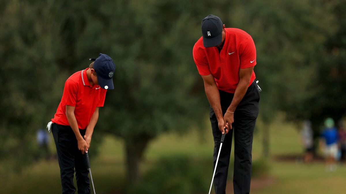 Tiger Woods and son Charlie Woods practice putting on the 14th hole. — AFP