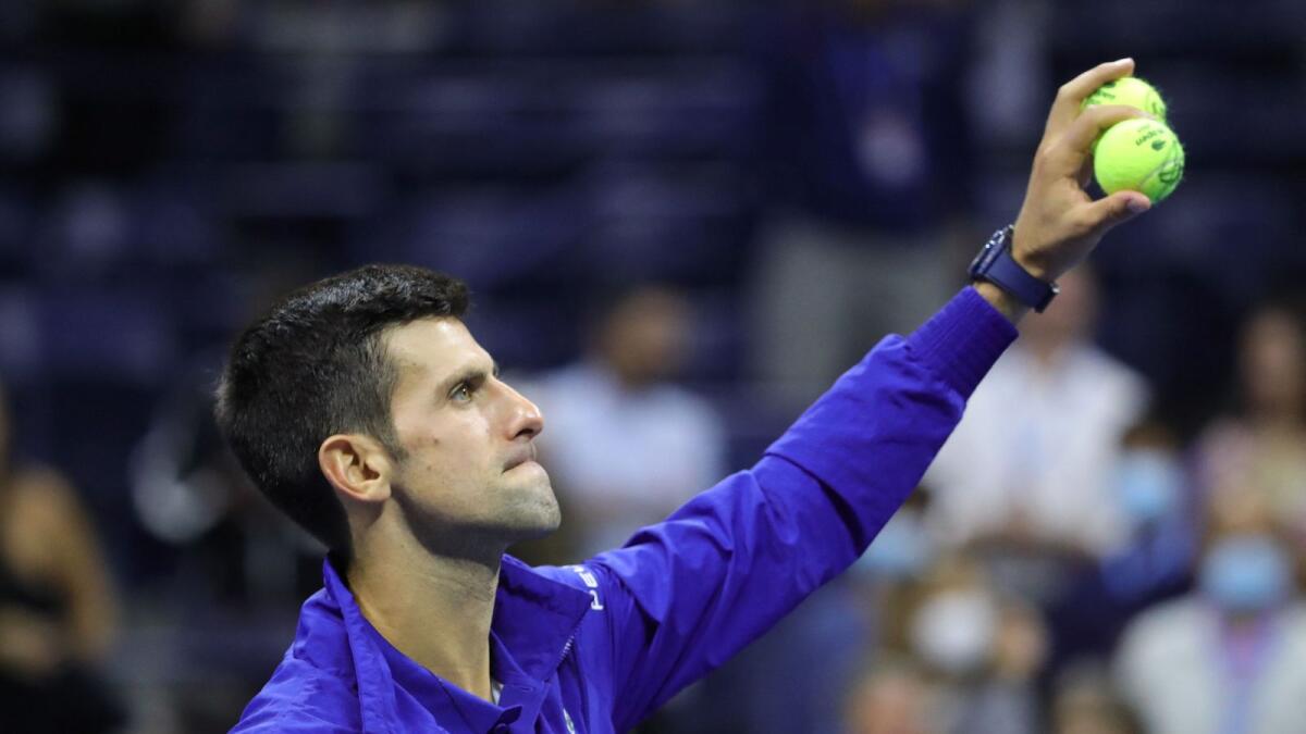 Serbia's Novak Djokovic throws tennis balls into the stands as he celebrates after winning his 2021 US Open Tennis tournament men's semifinal match against Germany's Alexander Zverev. — AFP