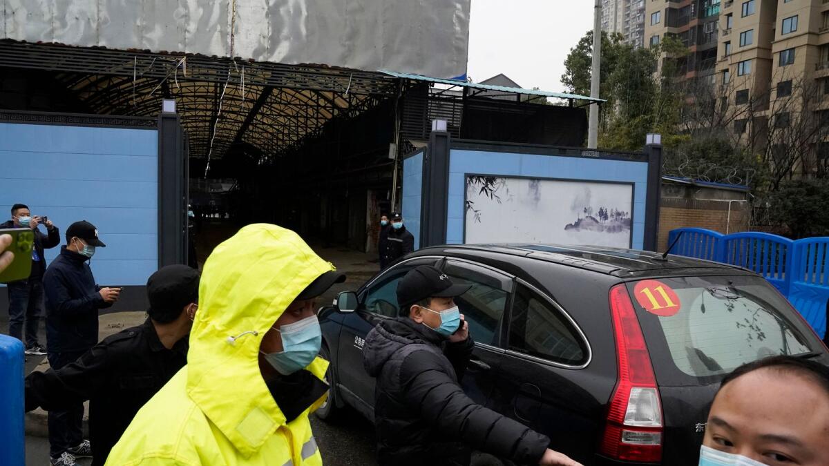 Security personnel clear the way for a convoy of the WHO team to enter the Huanan Seafood Market on the third day of field visit in Wuhan in 2021. — AP file