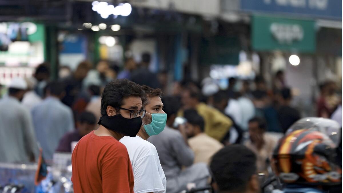 Men wearing protective masks walk along a market, as the coronavirus disease (Covid-19) outbreak continues, in Karachi. Photo: Reuters