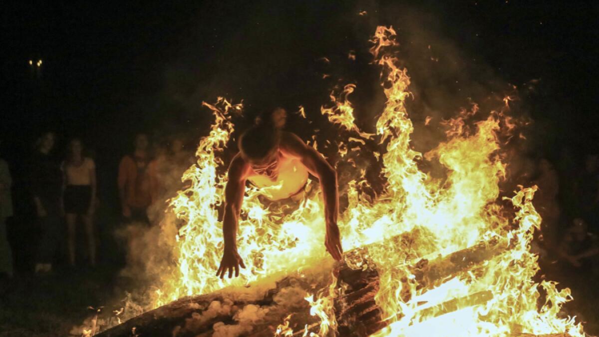 A young man jumps over the fire as people take part in a traditional mid-summer solstice night celebration (Rasos Festival) at the Open-Air Museum of Lithuania. Photo: AFP