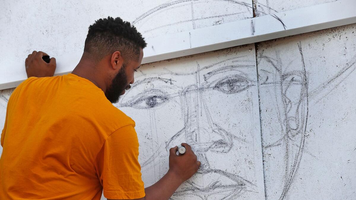 Matthew Cooper sketches out a face as he begins a triptych of murals on the Old Indianapolis City Hall, on Monday, June 8, 2020.  Black artists are painting murals on businesses that have been boarded up, after days of demonstrations.