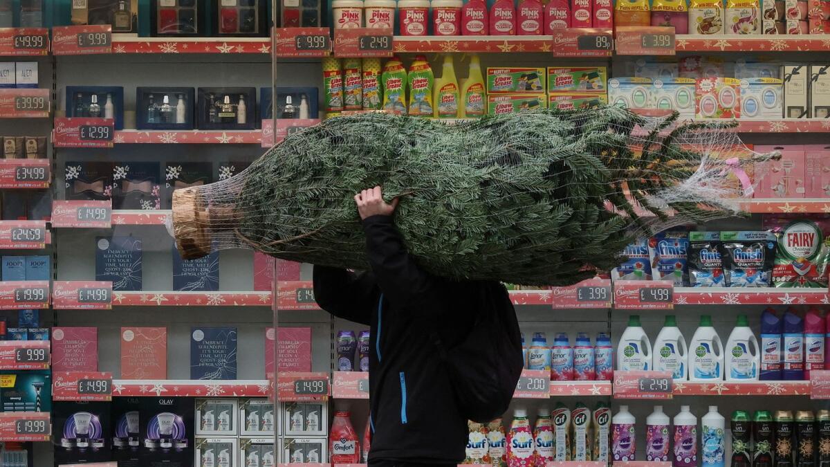 A man carries a Christmas tree amid the coronavirus disease outbreak, in Fulham, London. — Reuters