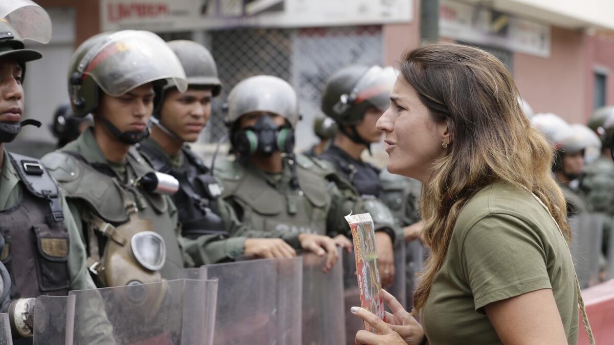 An opponent to Venezuela's President Nicolas Maduro faces riot police officers during a march in Caracas, Venezuela, Saturday, May 4, 2019. Opposition leader Juan Guaido took his quest to win over Venezuela's troops back to the streets, calling his supporters to participate in an outreach to soldiers outside military installations across the country.  AP