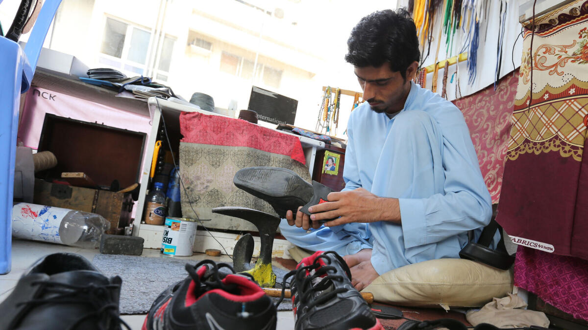 A man tries to fix a shoe at a repair shop near Salam Street in Abu Dhabi. -Photo by Ryan Lim/Khaleej Times