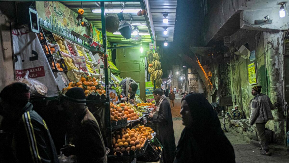 People walk past a fruit seller's stall in the Azhar district of Egypt's capital Cairo. — AFP